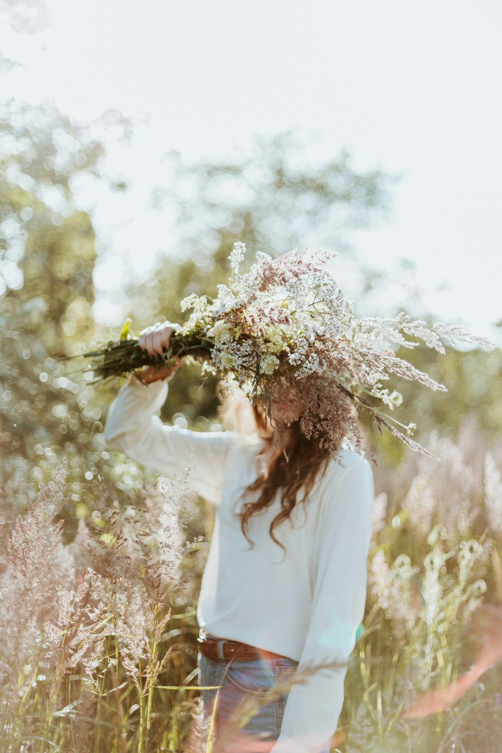 Une femme debout dans un champ avec un bouquet de fleurs sur la tête