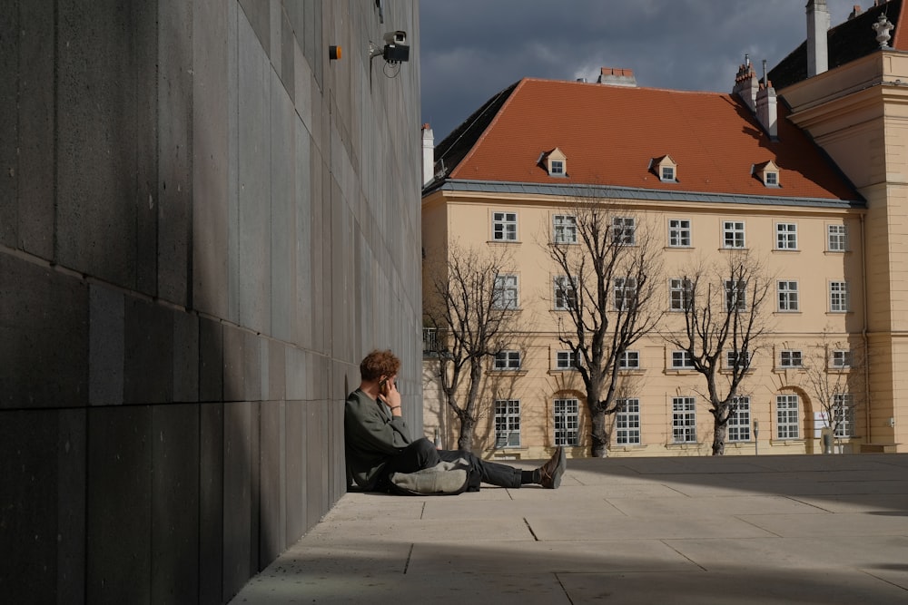 Mujer en chaqueta negra sentada en piso de concreto gris durante el día