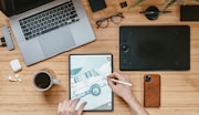 person holding black ipad near macbook pro