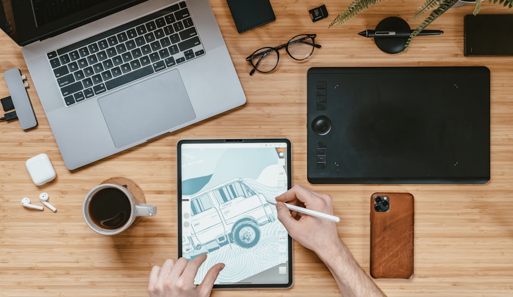 Person, die ein schwarzes iPad in der Nähe des MacBook Pro hält