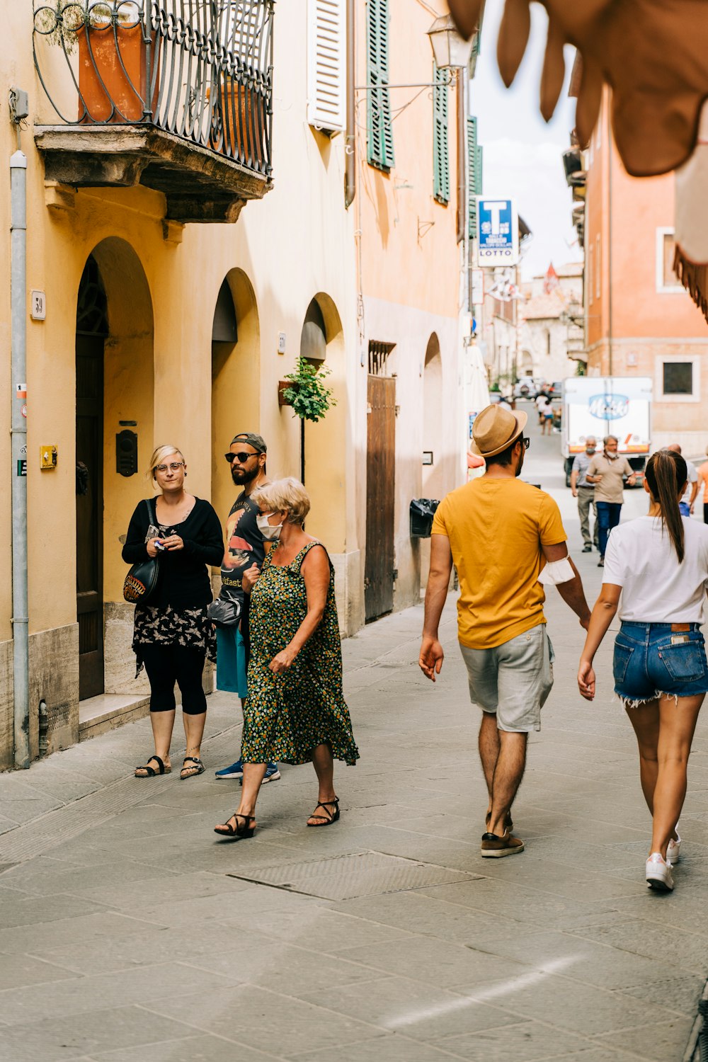 homme en t-shirt à col rond orange debout à côté d’une femme en robe à fleurs noire et blanche