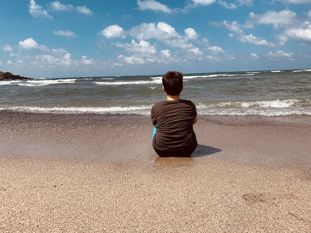 woman in black shirt sitting on beach during daytime