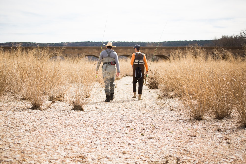 2 men walking on dirt road during daytime