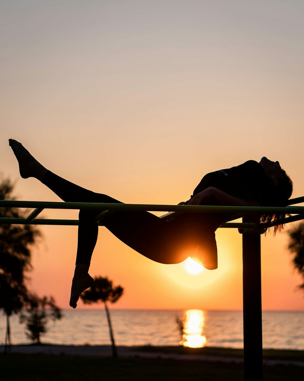 Silhouette einer Frau, die während des Sonnenuntergangs Yoga macht