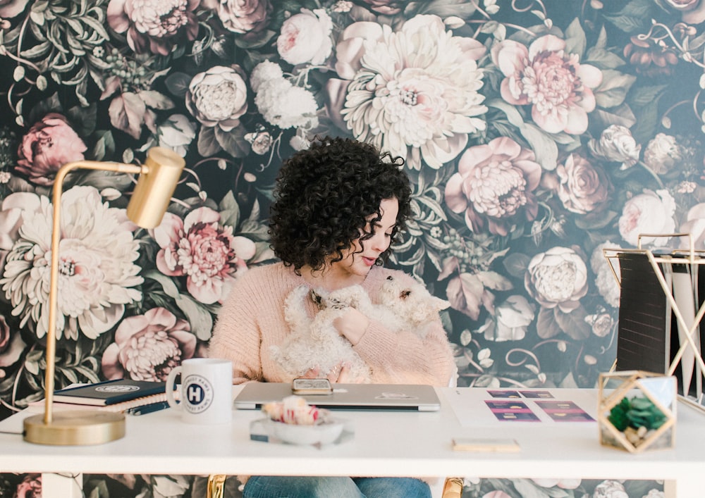 Femme en pull rose assise près de la table