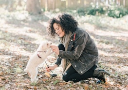woman in black jacket holding white dog