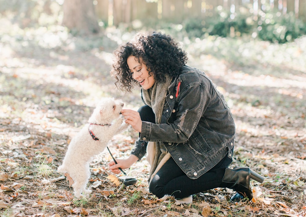 woman in black jacket holding white dog