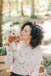 woman in white sweater holding white bear plush toy