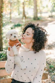woman in white sweater holding white bear plush toy
