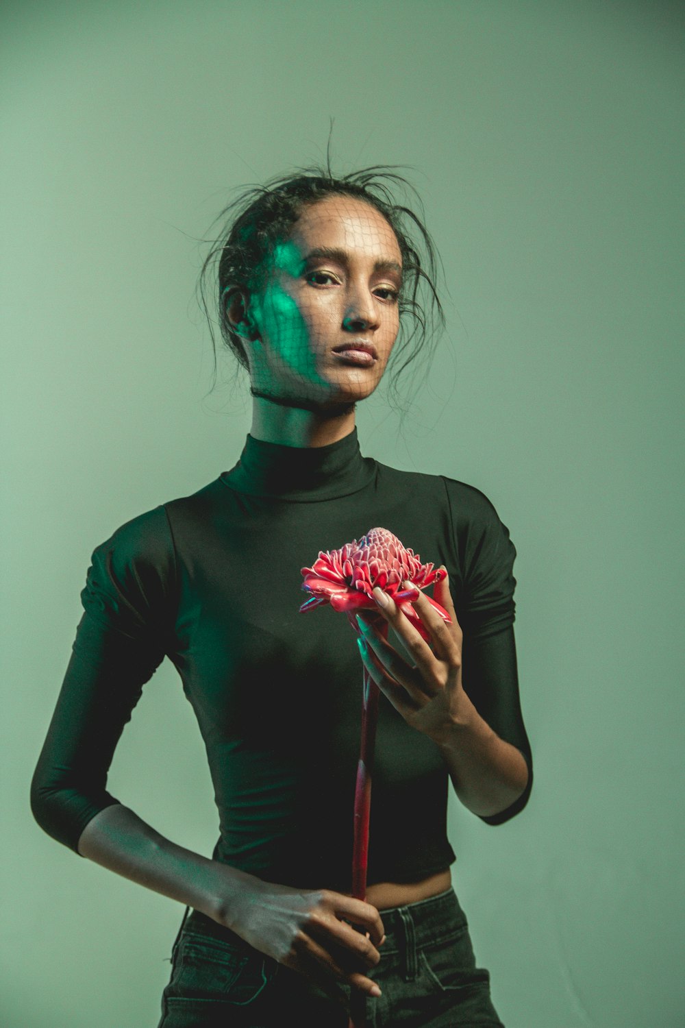 man in black long sleeve shirt holding red and white flower