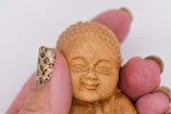 A small thumbnail of a wooden carved figurine with its name below.