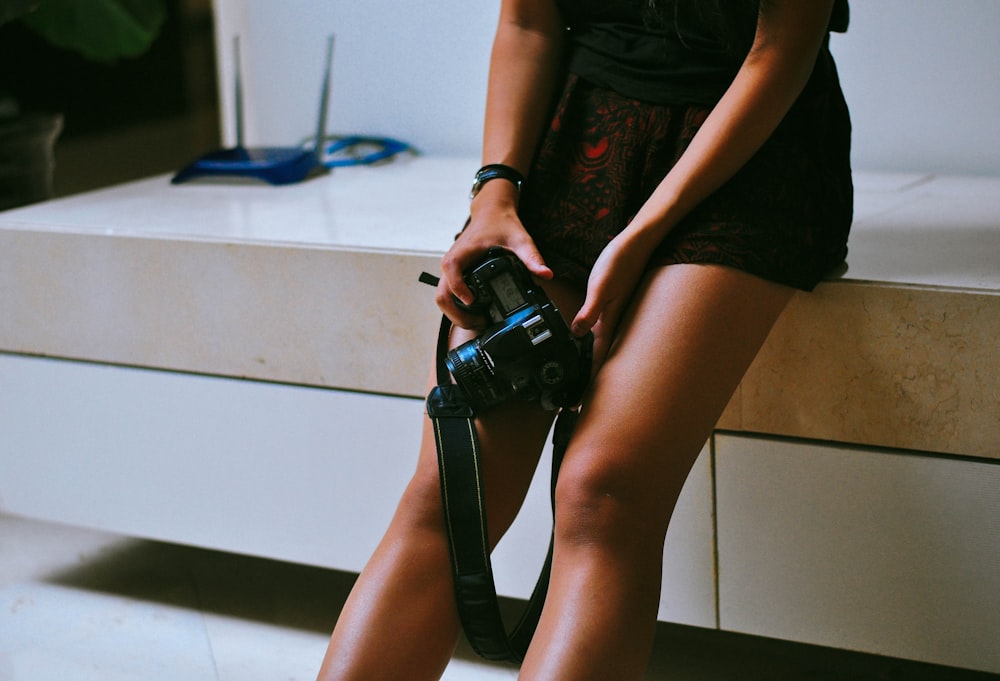 woman in black t-shirt and black shorts holding black dslr camera