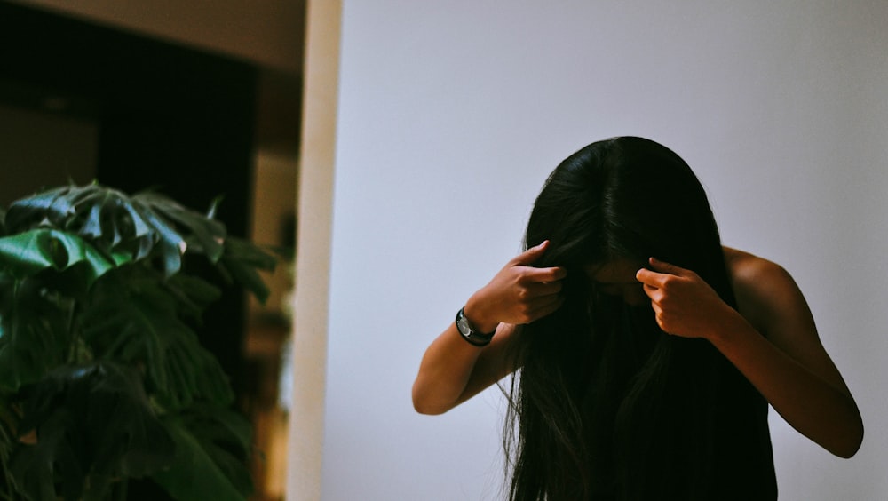 woman in black shirt covering face with hair