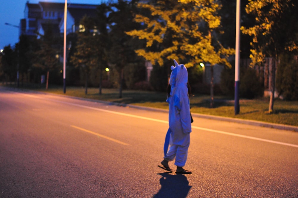 man in blue jacket and black pants walking on road during daytime