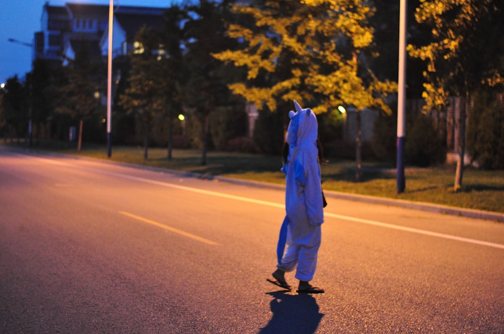 Mann in blauer Jacke und schwarzer Hose geht tagsüber auf der Straße spazieren