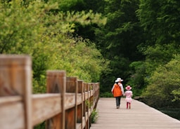 2 women walking on wooden bridge during daytime