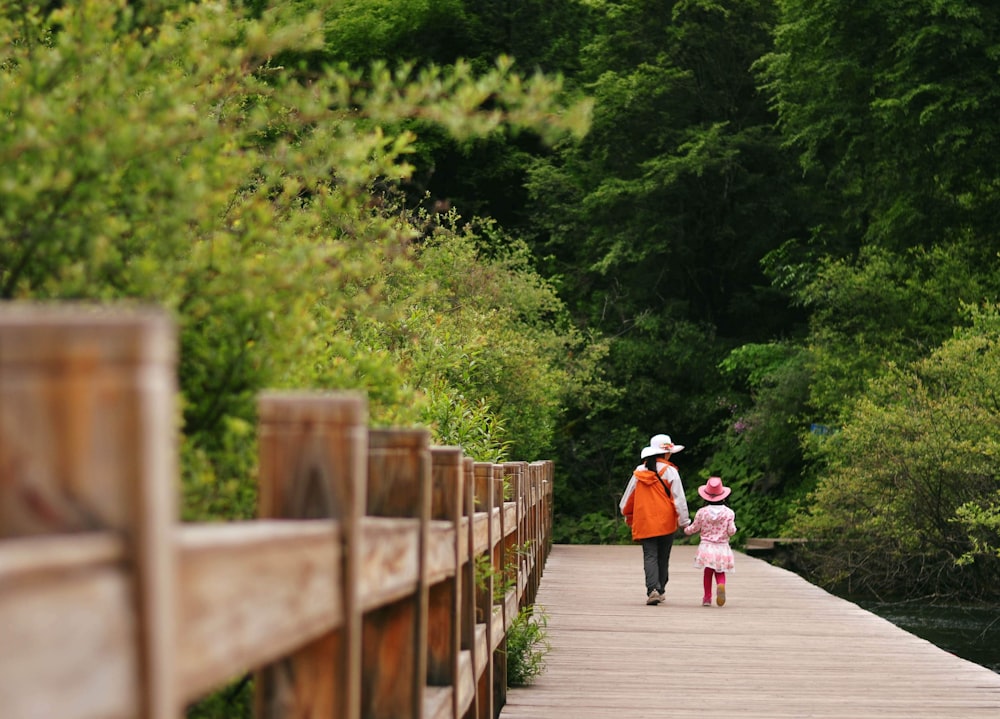 2 femmes marchant sur un pont en bois pendant la journée