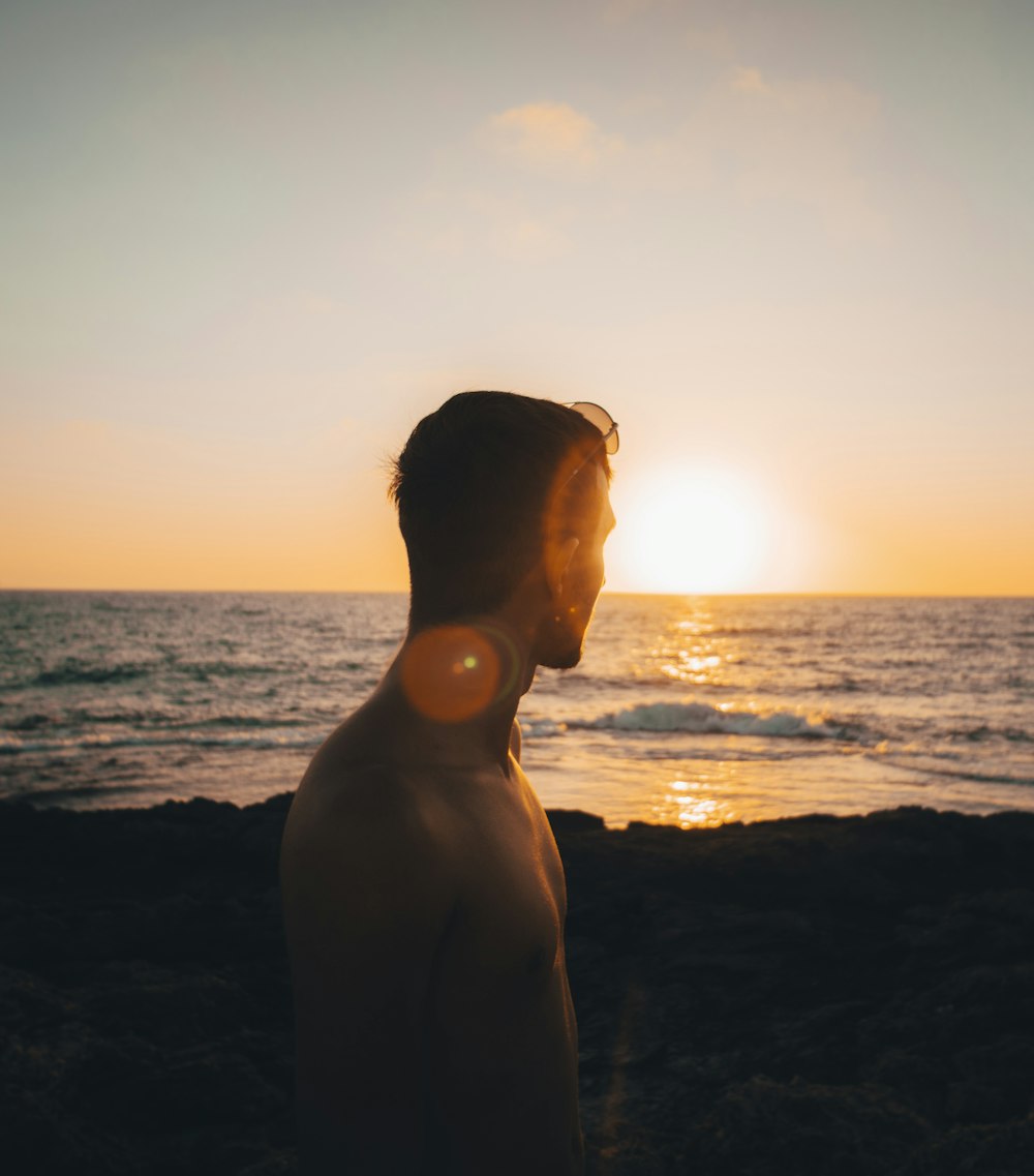 silhouette of man standing on beach during sunset