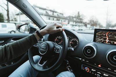 A learner driver attentively following a GPS route on a sunny suburban street.