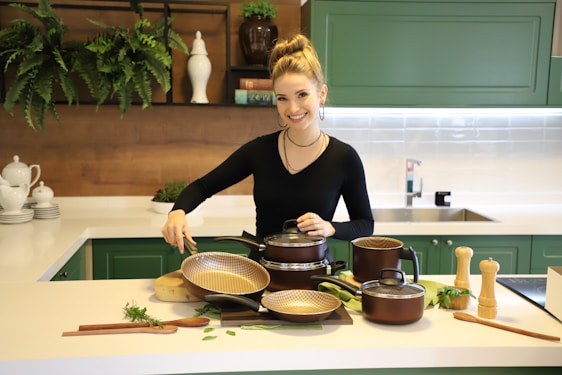 Nouf Alwatban smiling warmly in a bright, airy kitchen surrounded by fresh fruits and vegetables.
