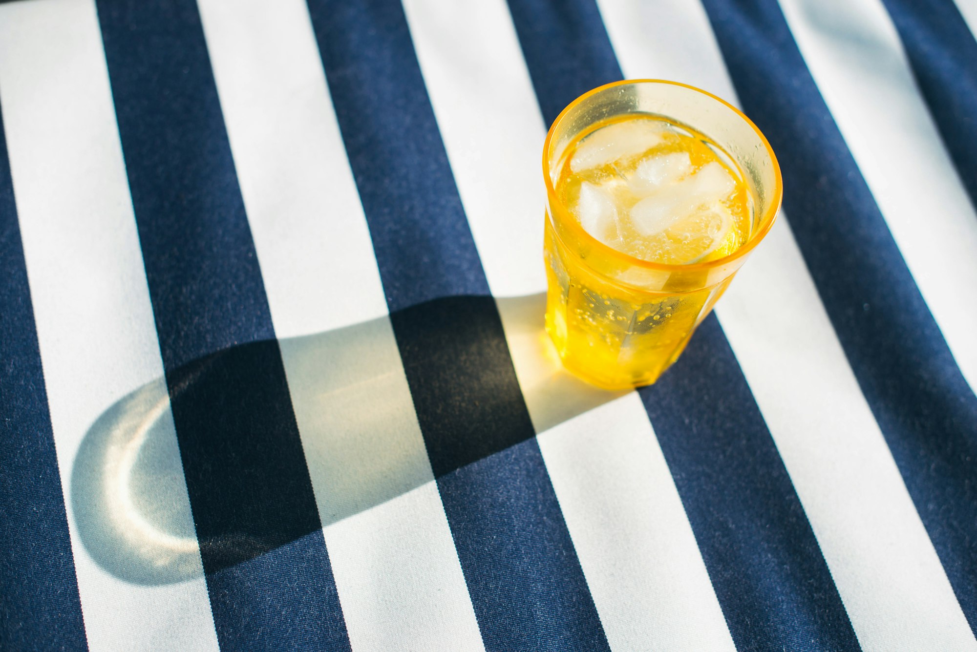 Drink in yellow cup on striped towel at nautical themed party.