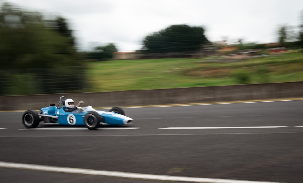 a blue race car driving down a road
