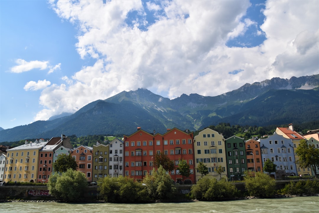 brown and white concrete buildings near green trees under white clouds and blue sky during daytime