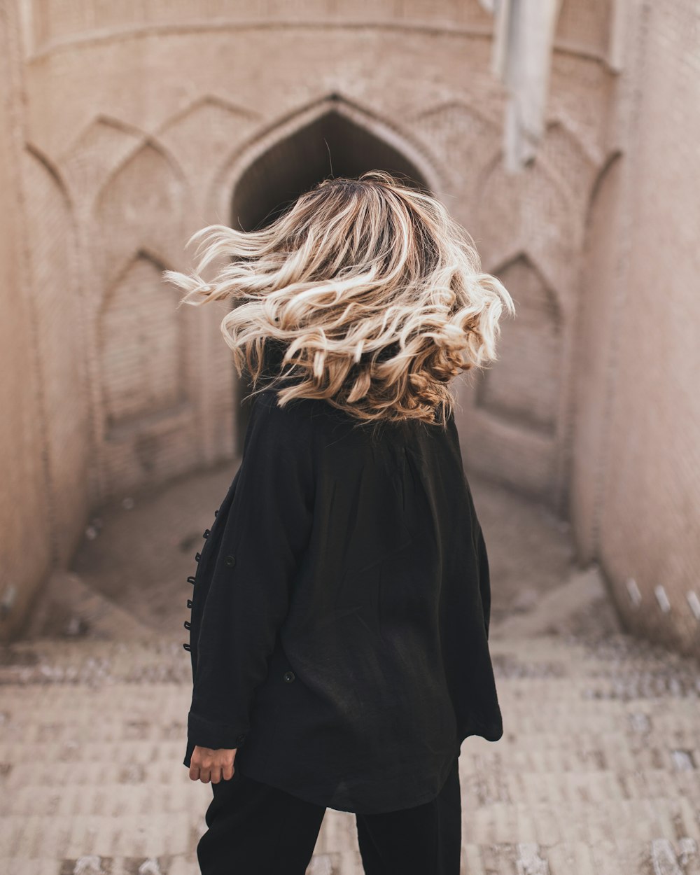 woman in black long sleeve dress standing near brown concrete wall during daytime