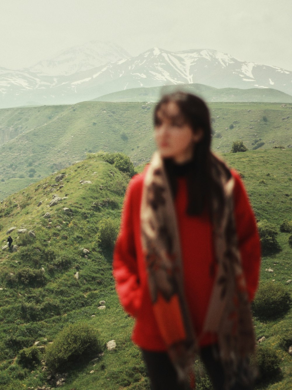 woman in red and black jacket standing on green grass field during daytime