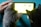 Two cats are facing a smartphone with a bright screen, seemingly captivated by what is displayed. A human hand is holding the device, suggesting interaction or facilitation. The scene conveys a sense of curiosity and technology interaction involving pets.