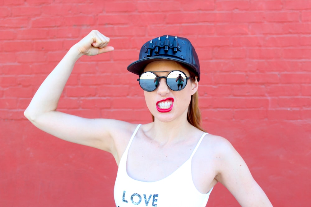 woman in white tank top wearing black sunglasses and blue and white fitted cap