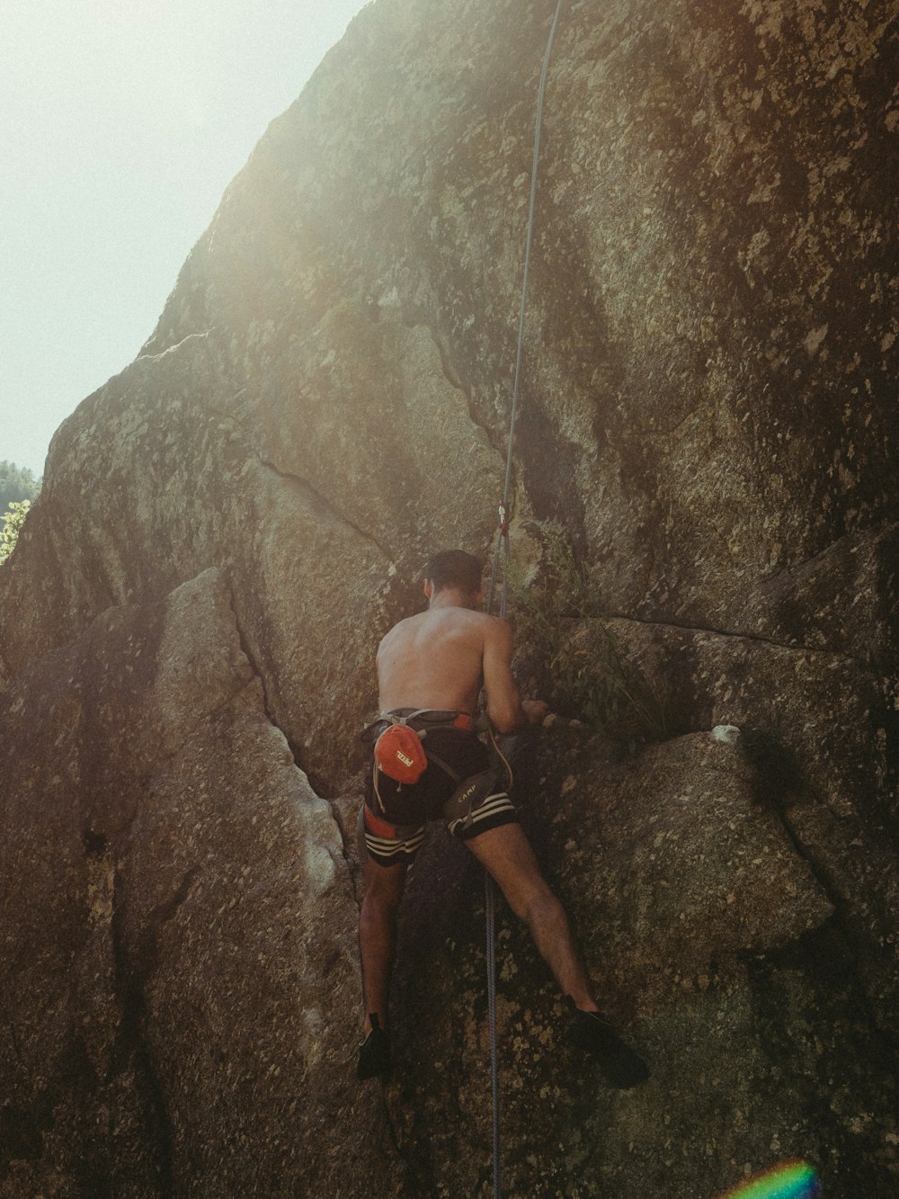man in black shorts climbing on rocky mountain during daytime