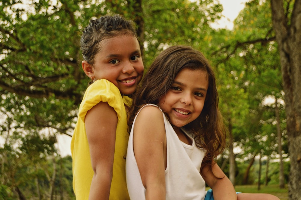 woman in white tank top beside girl in yellow dress