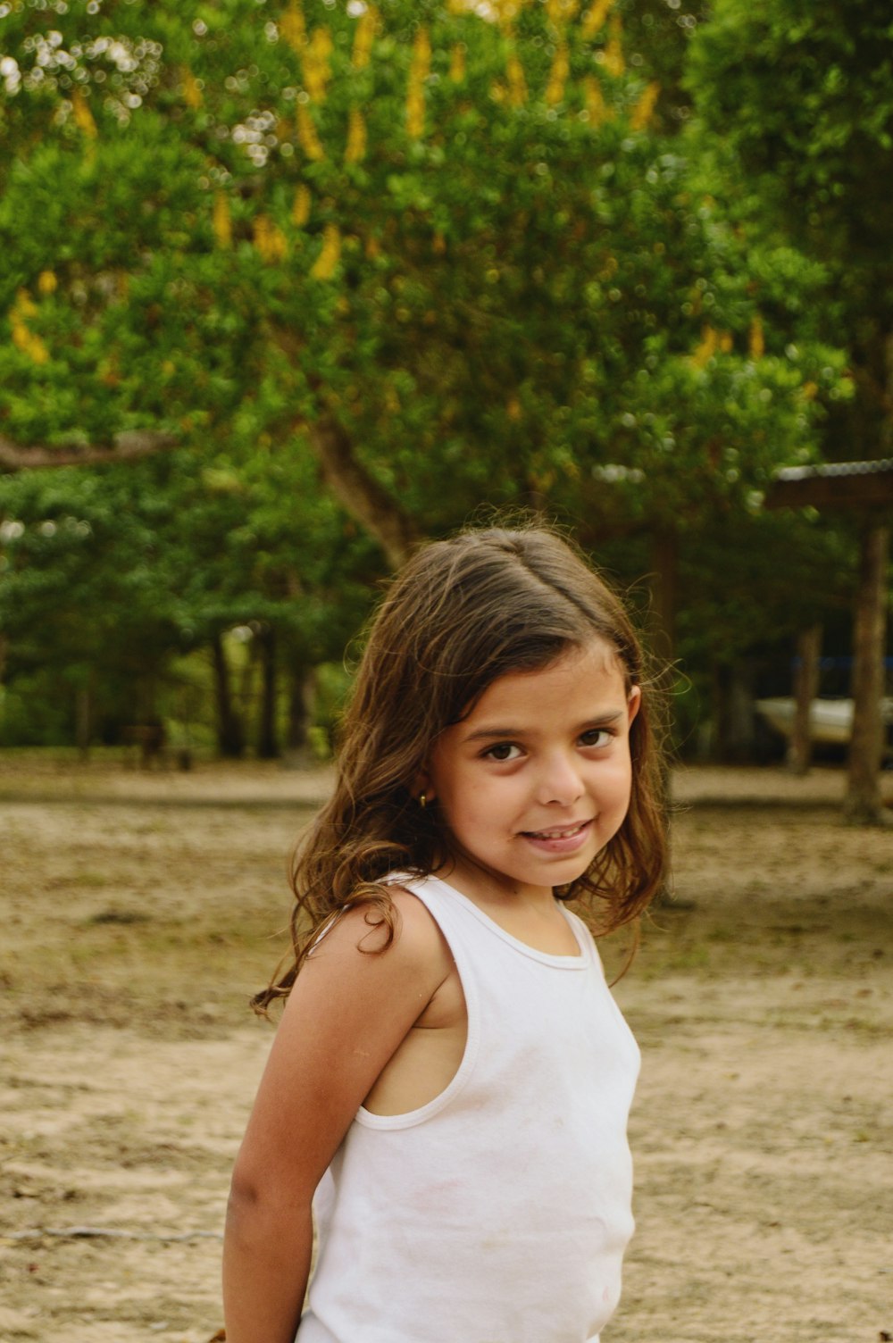 girl in white tank top standing on brown field during daytime