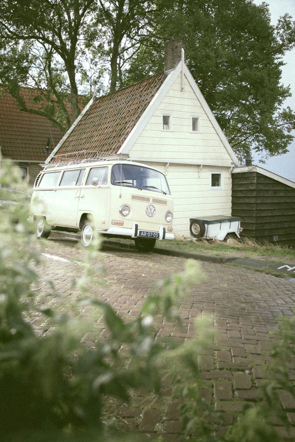 茶色のレンガ造りの家の横に駐車された白いフォルクスワーゲンT-2