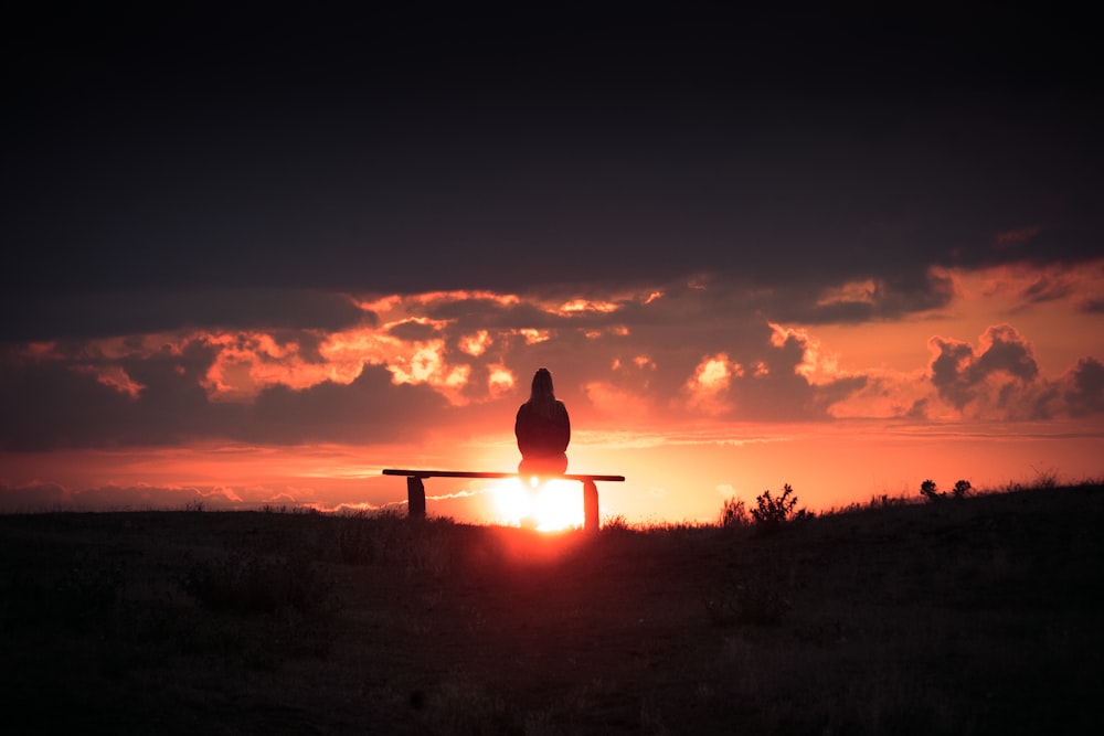 silhouette of person sitting on bench during sunset