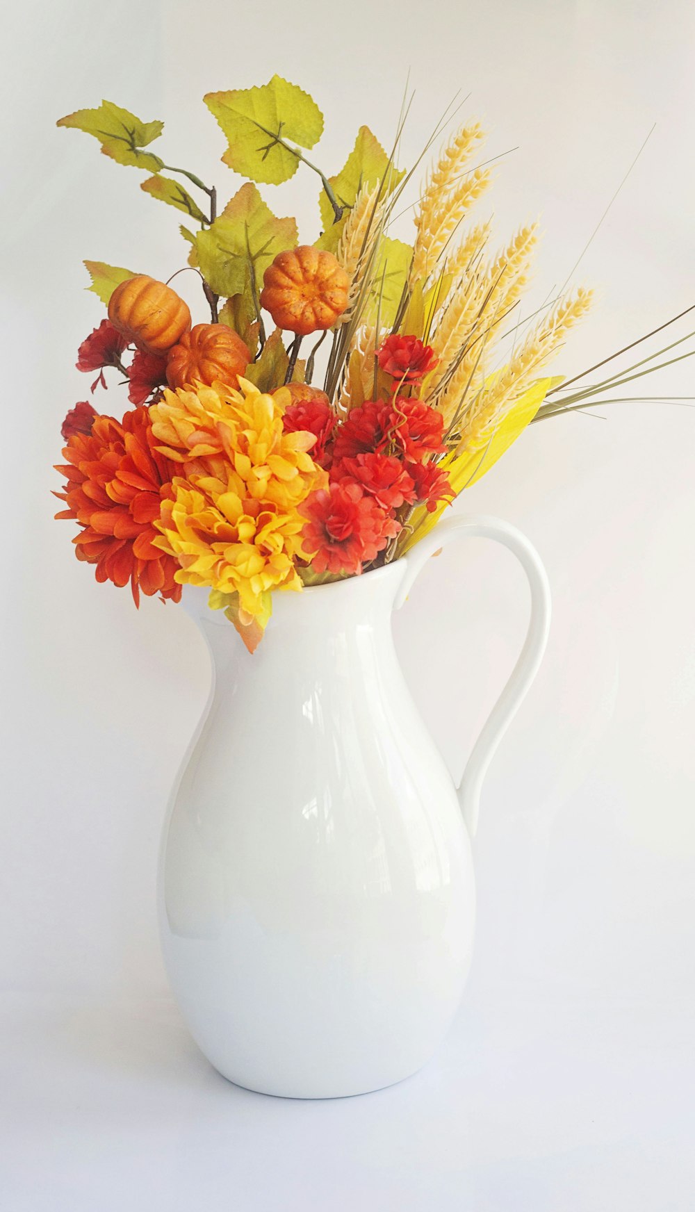 yellow and red flowers in white ceramic vase