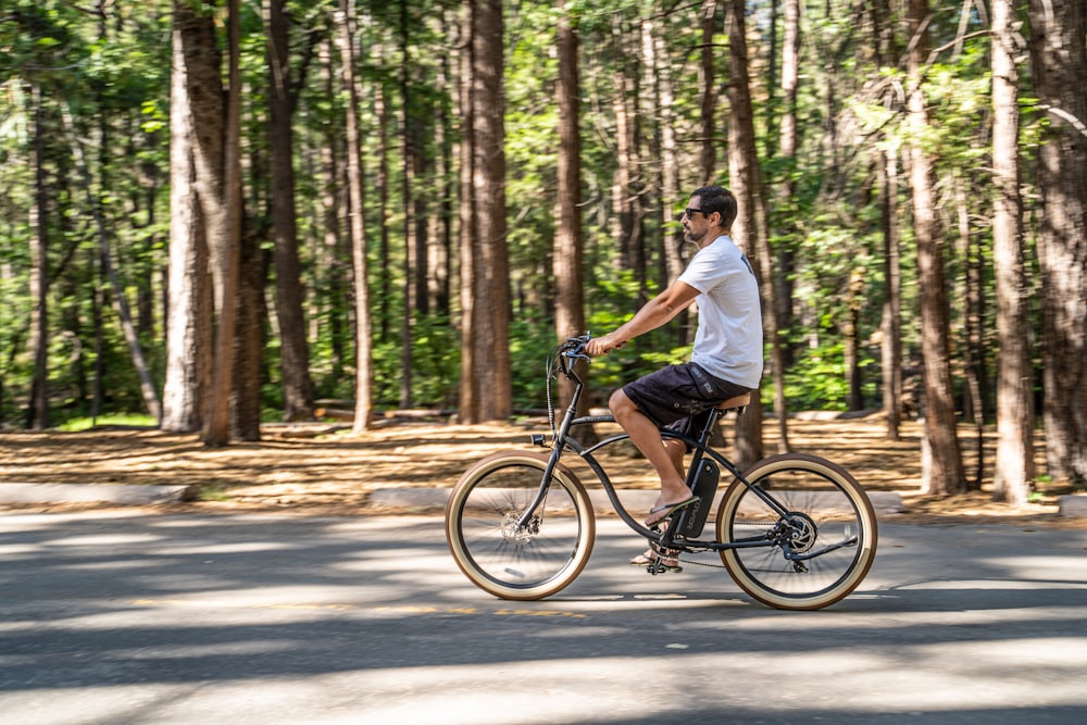 man in white t-shirt riding on bicycle in the middle of the road during daytime