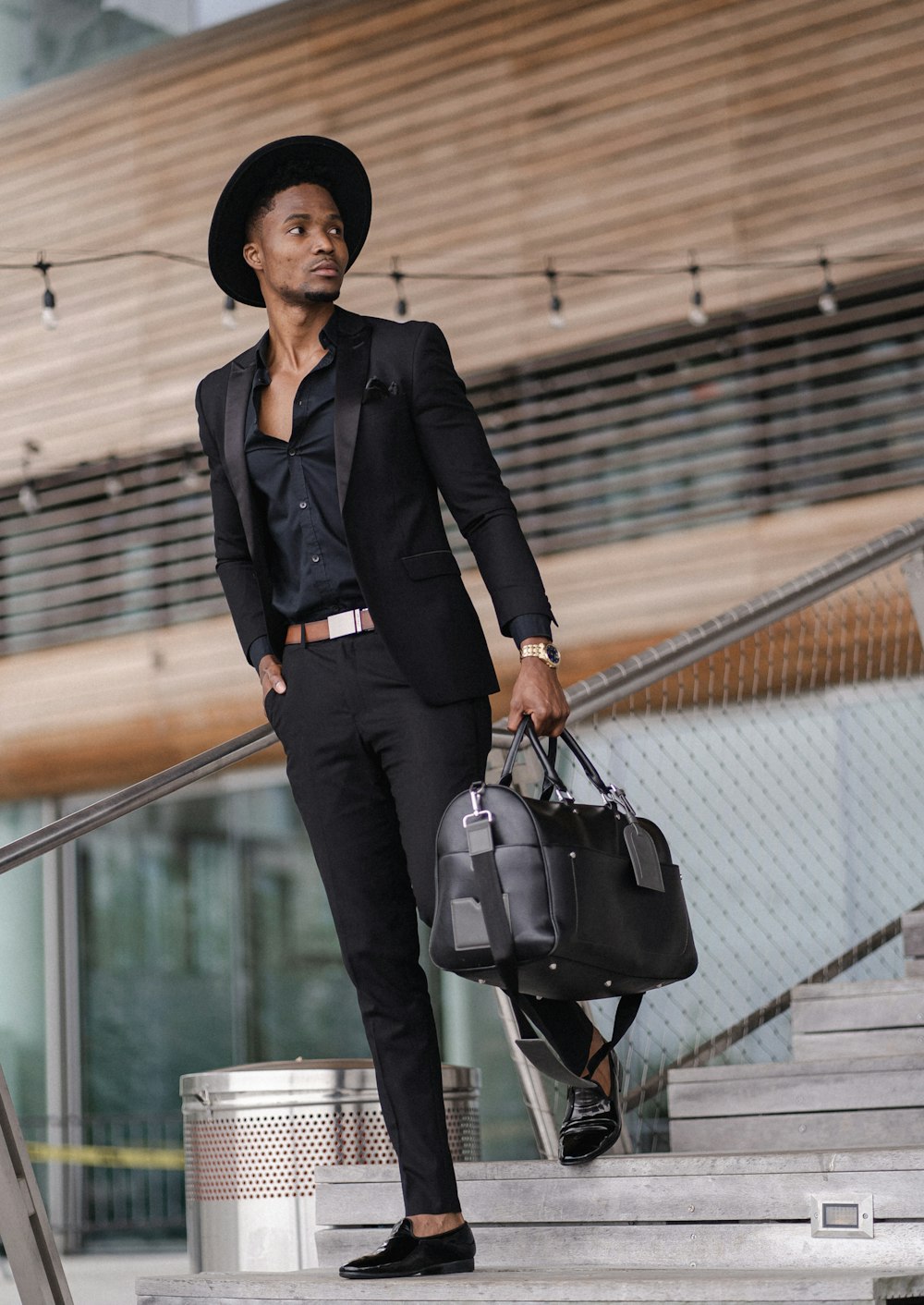 woman in black blazer and black pants with black leather shoulder bag standing on stairs