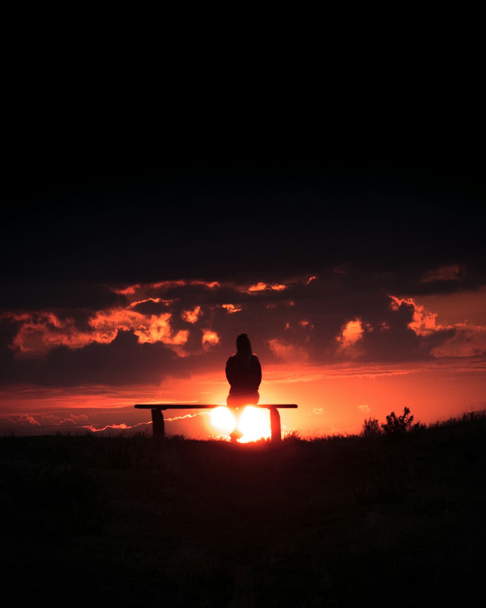 silhouette of person standing on grass field during sunset