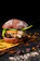 Close-up of a sizzling Burgaroo Majic burger with melted cheese and fresh toppings on a dark plate.