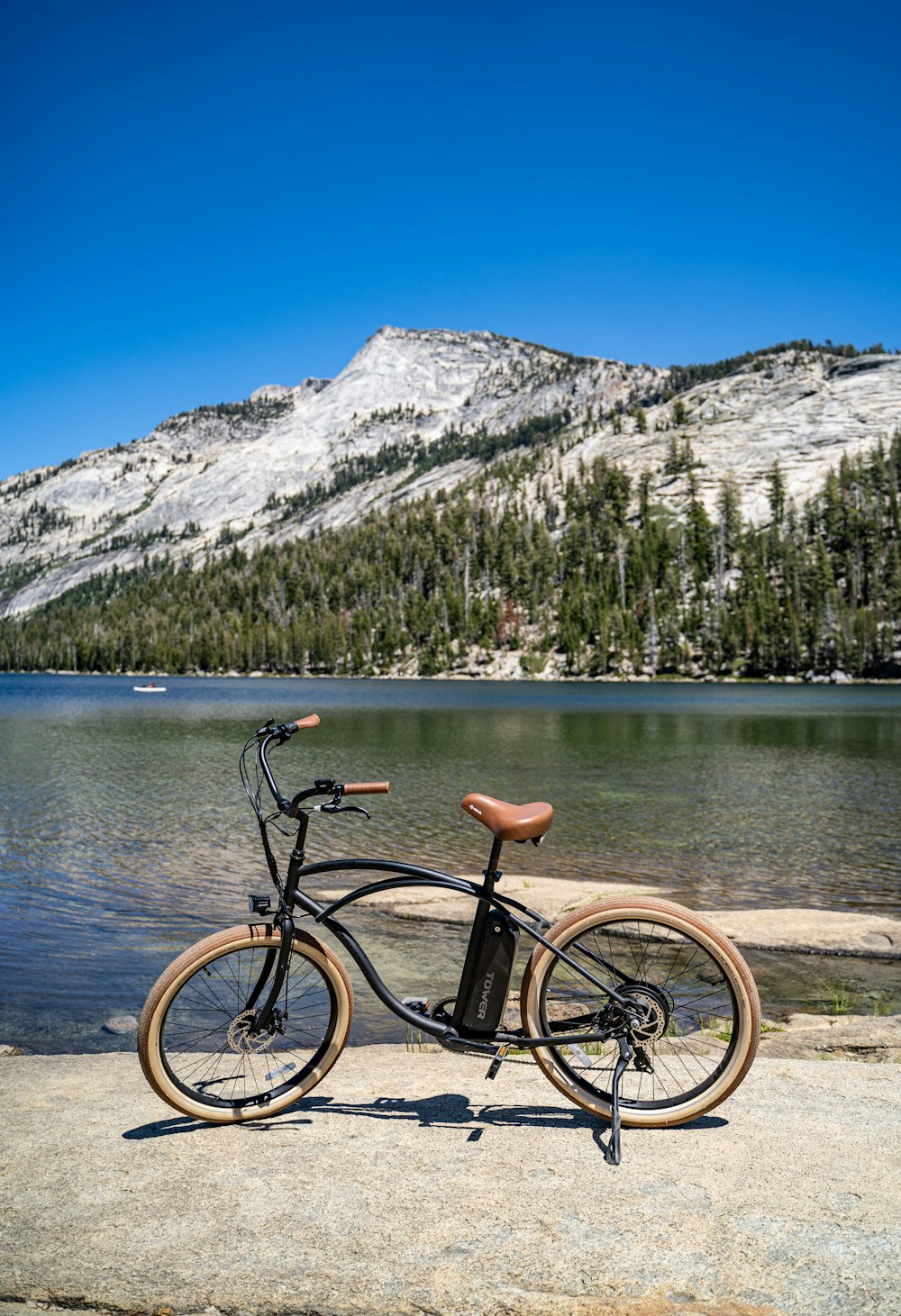 Bicicleta negra en muelle de madera marrón cerca del lago durante el día