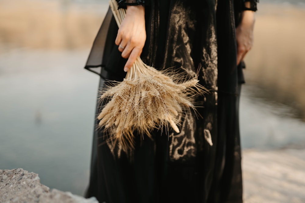 woman in black long sleeve dress holding brown dried grass