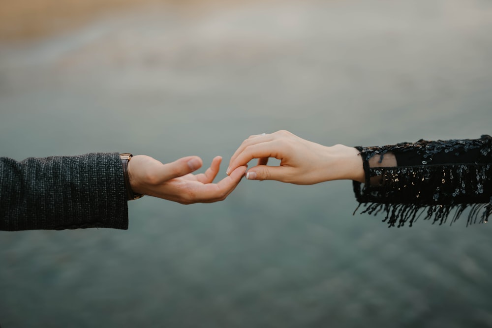 person in black long sleeve shirt holding hands with woman in black long sleeve shirt