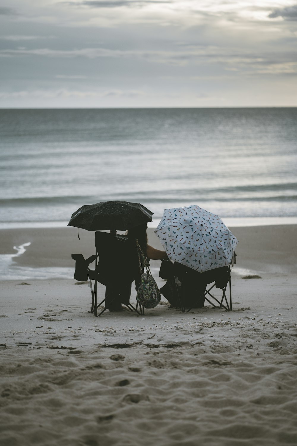 personne tenant un parasol marchant sur la plage pendant la journée