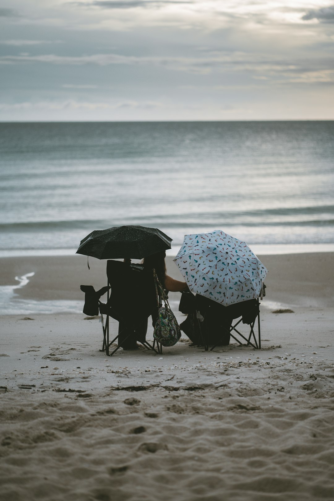 person holding umbrella walking on beach during daytime