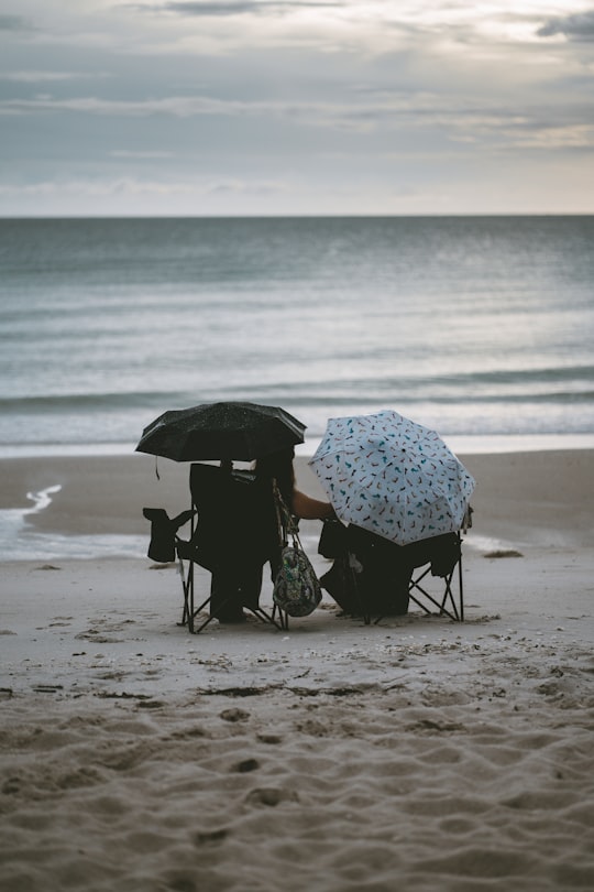 person holding umbrella walking on beach during daytime in Naples United States