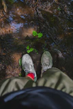 Olive-green anti-leech socks pulled high above the knee with wet leaves clinging, worn in a misty tropical jungle setting.