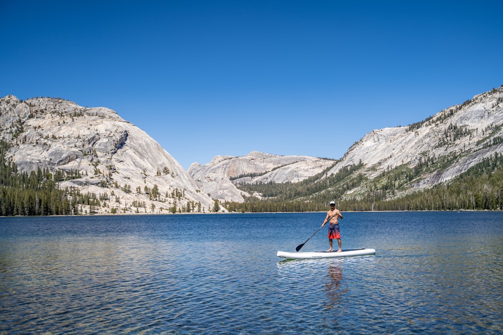 woman in red shirt riding white kayak on lake during daytime