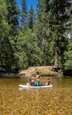 A family laughing and enjoying paddleboarding near the lakeshore with lush green hills in the background